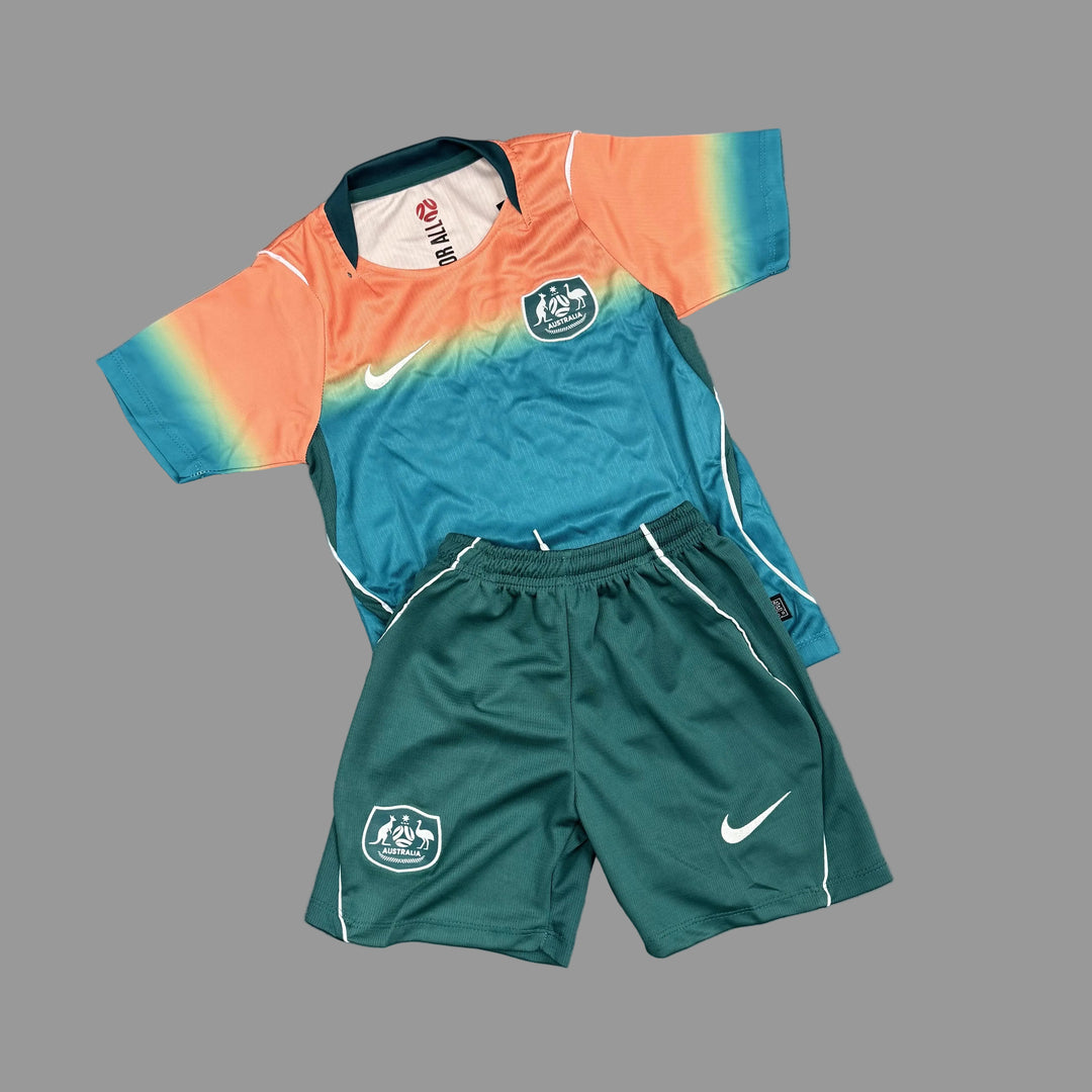 A vintage Nike soccer kit for the Australia national team, featuring a short-sleeve jersey with a teal, orange, and yellow gradient design, and matching dark green shorts with white accents, laid flat on a gray concrete floor.